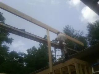 Carpenter setting a ridge beam over a new addition frame — Ice Dam Removal by Roofing Brothers in Lakewood