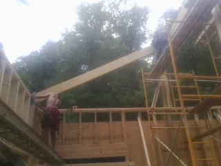 Carpenter raising a rafter beam on a new second story frame in Lakewood
