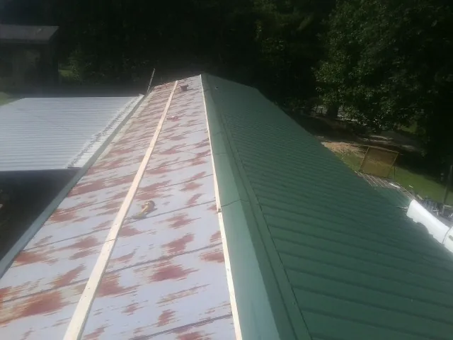 Old rusted panels beside newly installed green metal roofing — Wind Damage Roof Repair by Roofing Brothers in Lakewood