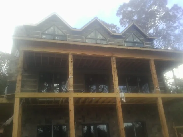 Dormers and porch framing on a large log home under construction — Roof Coating work by our crew in Lakewood